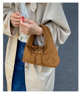 Detail einer braunen Wildleder-Handtasche mit Kordelzug und eleganten Metallperlen