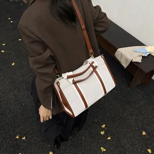 Retro canvas tote bag with brown leather trim and shoulder strap in outdoor autumn setting