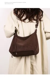 Detail of vintage brown suede tote bag with knot strap and fringe, shown on shoulder