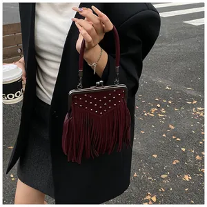 Detail of dark red vintage handbag featuring silver studs and long fringe tassels