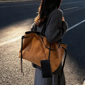 Sac cabas en daim marron avec texte embossé et détails de franges sur un mannequin