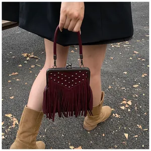 Detail of vintage burgundy tassel handbag with retro metal clasp and stud embellishments
