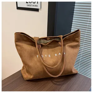 Detail view of brown suede tote bag with white text print and silver magnetic buckle