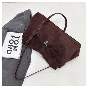 Detail view of large dark brown suede tote bag with silver twist lock and slim strap