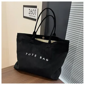 Detail of minimalist black tote bag with silver magnetic closure and interior lining