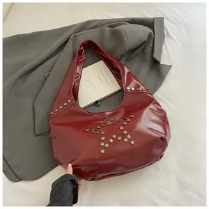Detalle del bolso hobo de charol burdeos con decoración de remaches de estrellas plateadas