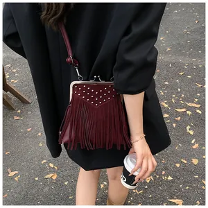 Detail of burgundy suede crossbody bag with silver studs and long fringe tassels