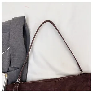Close-up of dark brown suede shoulder bag with contrast stitching and silver hardware