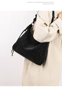 Detail of black suede hobo bag featuring woven rope knot strap and metallic drawstring