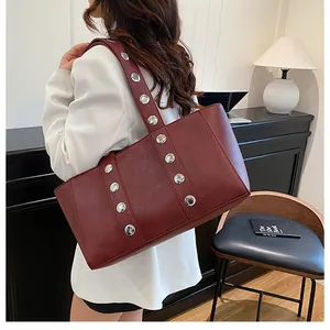 Macro shot of stylish burgundy tote bag with silver rivets and leather texture details
