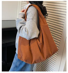 On-shoulder view of a large caramel brown corduroy tote bag for casual autumn styling