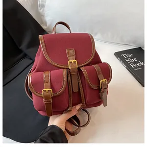 Detail van bordeauxrode mini-rugzak van imitatie suède met leren bies en gespen