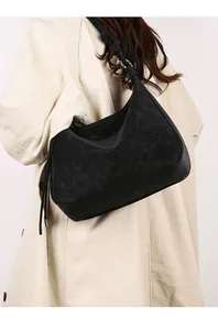 Close-up of decorative strap knots and silver metal rings on a black suede hobo bag