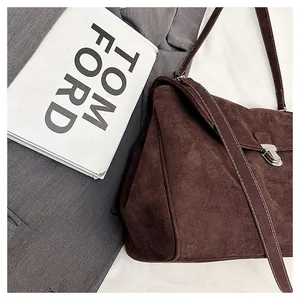 Detail of dark brown suede handbag with white stitching and silver metal buckle closure