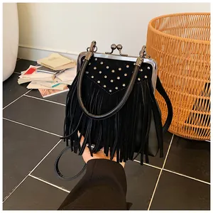 Detailed close-up of retro black suede handbag featuring long fringes and silver stud accents