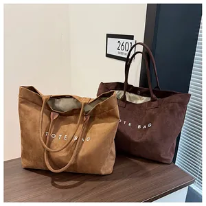 Detailed view of two brown suede tote bags with TOTE BAG print on a wooden surface