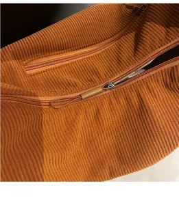 Close-up of smooth zipper on orange corduroy tote bag showing striped fabric texture