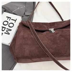 Detail of dark brown suede shoulder bag featuring silver buckle and contrast stitching