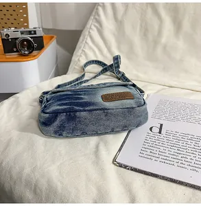 Détail d'un sac bandoulière en denim délavé avec un écusson en cuir marron style urbain