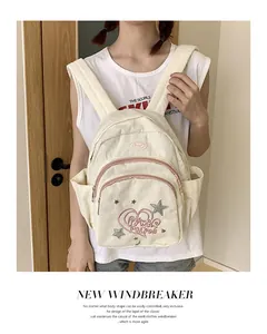 Gros plan d'un sac à dos en velours côtelé blanc cassé avec broderie d'étoiles et lettrage