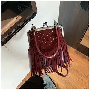 Close-up of burgundy fringe handbag featuring heavy-duty studs and vintage clasp detail
