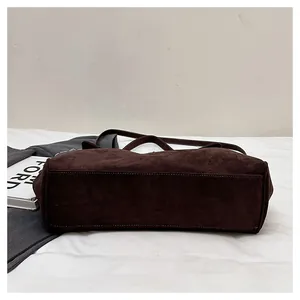 Detail view of the rectangular base and neat stitching on a brown suede tote bag