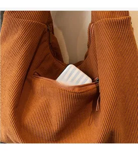 Detail of caramel corduroy tote bag featuring a practical front zipper pocket for accessories