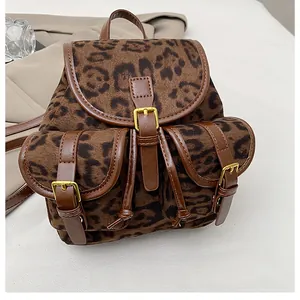 Detailopname van luipaardprint rugzak met bruine lederen riemen en gouden gesp