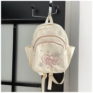 Détail d'un mini sac à dos en velours côtelé crème avec broderie cœur rose et texture