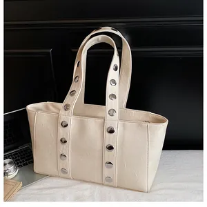 Detail of silver rivets and textured beige leather on a large casual shoulder tote bag