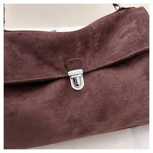 Detail of suede crossbody bag with vintage silver buckle and contrast stitching