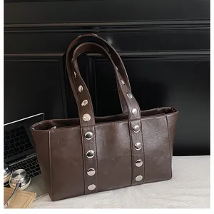 Detail of chocolate brown leather tote with silver rivets on straps for a vintage look