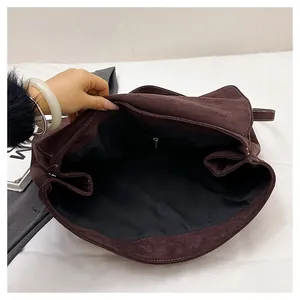 Interior detail of large brown suede shoulder bag featuring a smooth black lining with zipper pocket