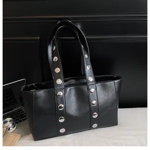 Close-up of black leather tote bag with silver studs on straps and spacious interior