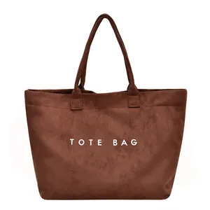 Brown suede tote bag with large TOTE BAG print and dual top handles for daily commuting