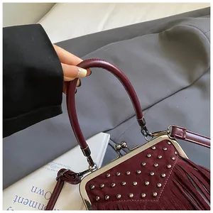 Detail shot of a wine red vintage handbag with silver rivets and fringe tassels
