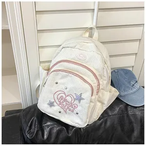 Détail d'un mini sac à dos en velours blanc avec cœur brodé rose et rivets étoile argent