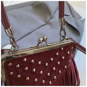 Detail of vintage burgundy suede bag featuring silver rivets and tassel fringe trim