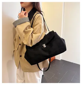 Detail view of a large black suede shoulder bag with a silver metal clasp for women
