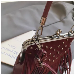 Detailed close-up of dark burgundy tassel bag with silver rivets and vintage metal clasp
