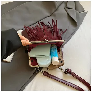 Detailed view of burgundy fringe bag showing interior capacity and silver rivet hardware
