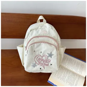 Détail d'un mini sac à dos en velours côtelé blanc avec broderie cœur et paillettes