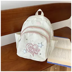 Détail d'un sac à dos en velours côtelé crème avec fermetures roses sur un banc en bois