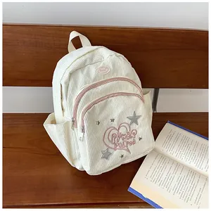 Gros plan d'un sac à dos en velours côtelé blanc avec broderie cœur et patchs d'étoiles