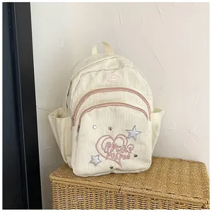 Détail du sac à dos en velours côtelé crème avec broderie cœur rose et étoiles