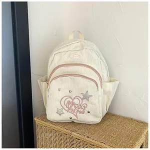 Détail d'un mini sac à dos en velours côtelé crème avec zip rose et broderie d'étoiles
