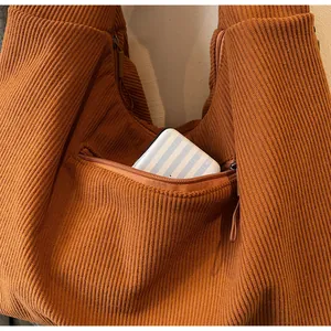 Detail of caramel ribbed tote bag featuring a practical external zipper storage pocket