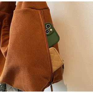 Detail of caramel corduroy tote showing a side zipper pocket holding a phone and wallet