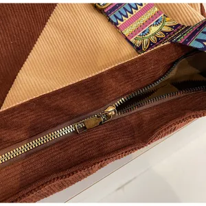Detail of corduroy patchwork shoulder bag featuring ethnic patterned strap and metal zipper
