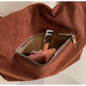 Close-up of front zipper pocket on brown corduroy tote bag showing practical storage capacity